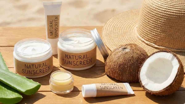 Jars and tubes of Natural Sunscreen with aloe vera and coconuts on a beach table