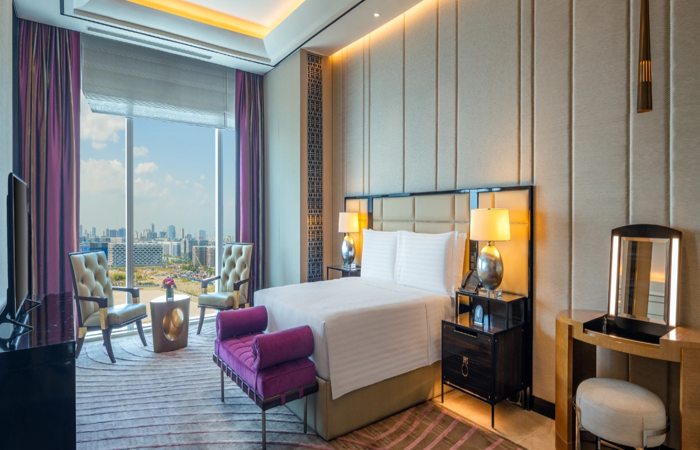 Luxury hotel room with king bed, seating area and city view window